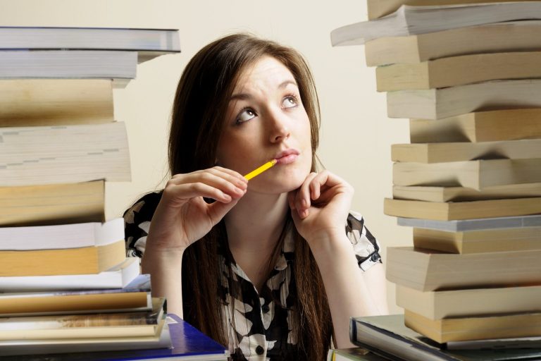 Photo: Woman in library surrounded by books, not getting on well with studies